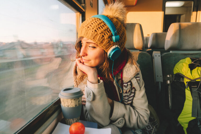 Ung kvinne på toget med hodetelefoner.