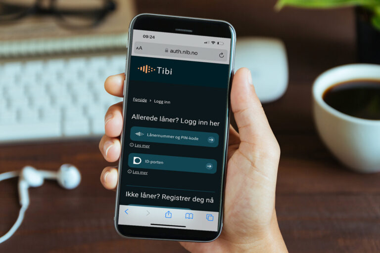Hånd holder mobil med tibi.no, innloggingssiden