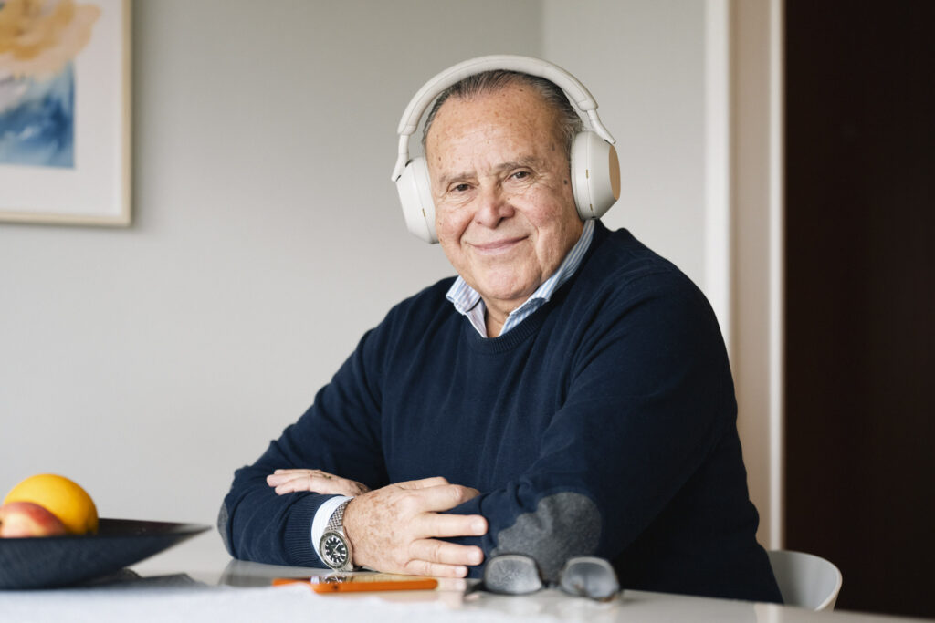 Smilende eldre låner med hodetelefoner sitter ved bordet