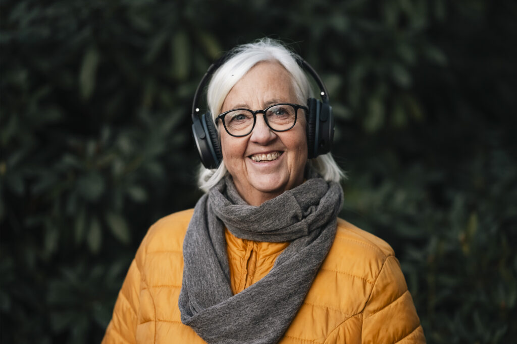 Smilende eldre låner med hodetelefoner