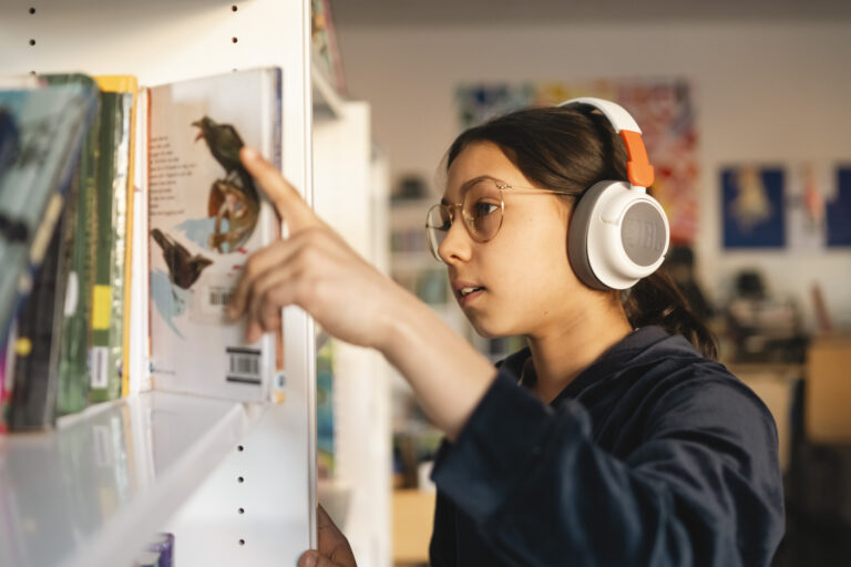 Jente ser i bokhyllen i et bibliotek