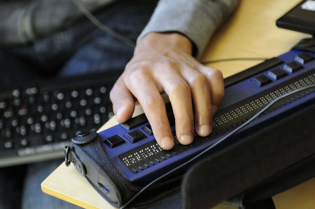 En hånd på en leselist og et tastatur i bakgrunnen.
